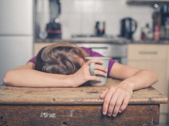 Tired woman with tea in kitchen
